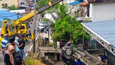 Istimewa - Proses evakuasi kendaraan dinas Toyota Rush yang terbalik di pekarangan rumah warga