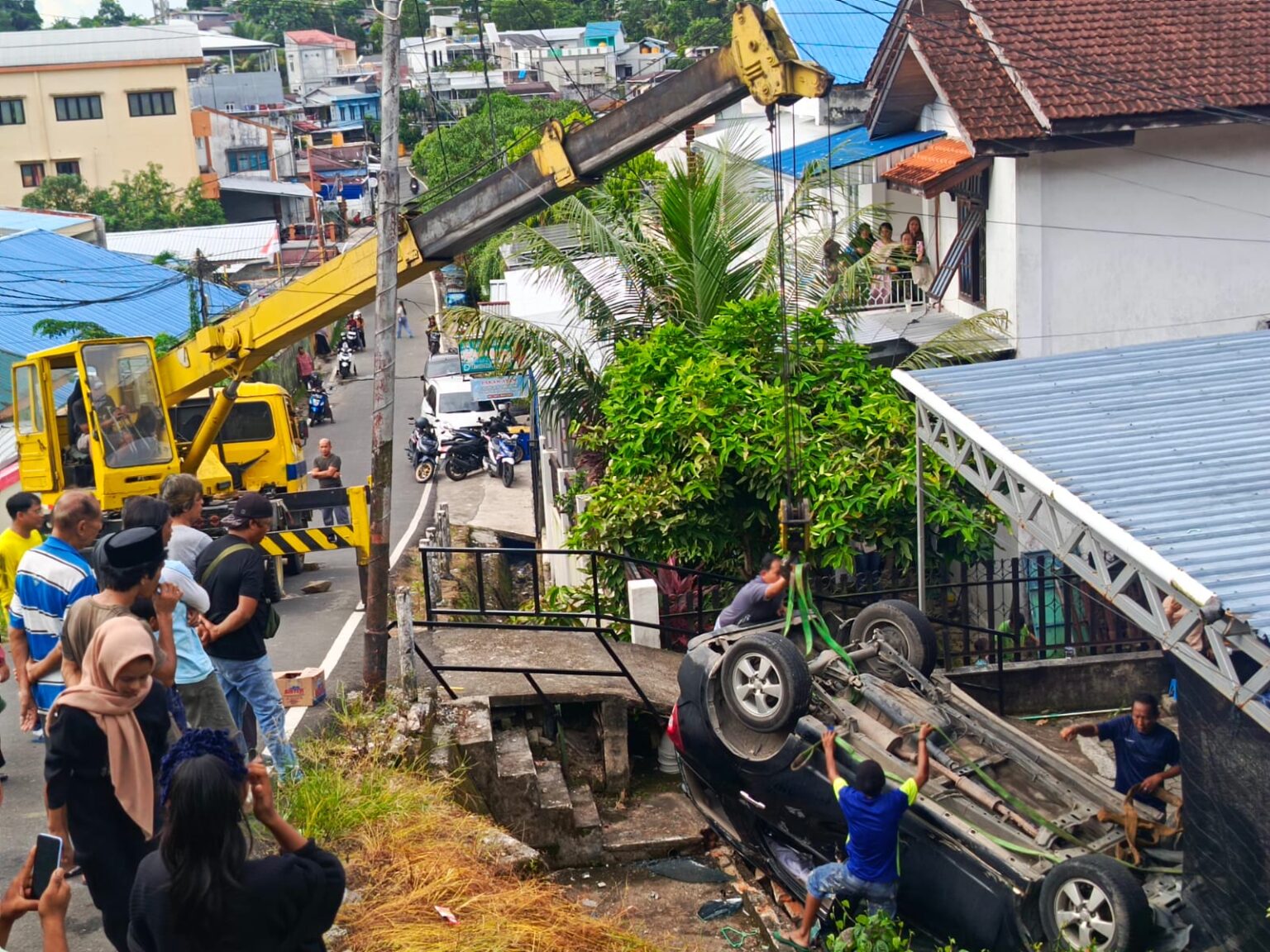 Istimewa - Proses evakuasi kendaraan dinas Toyota Rush yang terbalik di pekarangan rumah warga